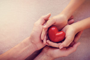 adult and child hands holiding red heart, health care love, give, hope and family concept